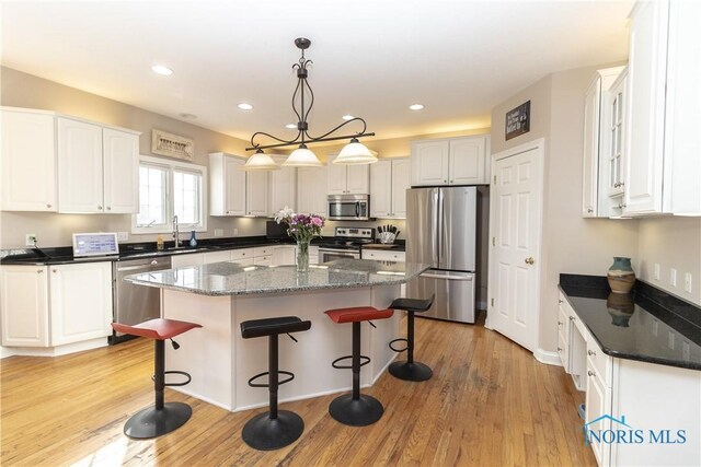 kitchen featuring white cabinetry, a center island, stainless steel appliances, and light wood-type flooring