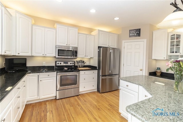 kitchen with white cabinetry, light hardwood / wood-style floors, appliances with stainless steel finishes, pendant lighting, and light stone counters