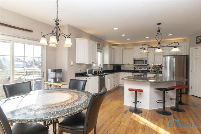 kitchen with white cabinets, hanging light fixtures, appliances with stainless steel finishes, and a kitchen island