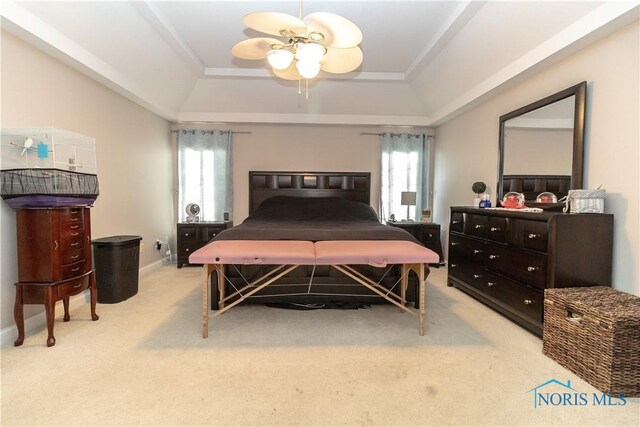 bedroom with ceiling fan, light carpet, and a tray ceiling