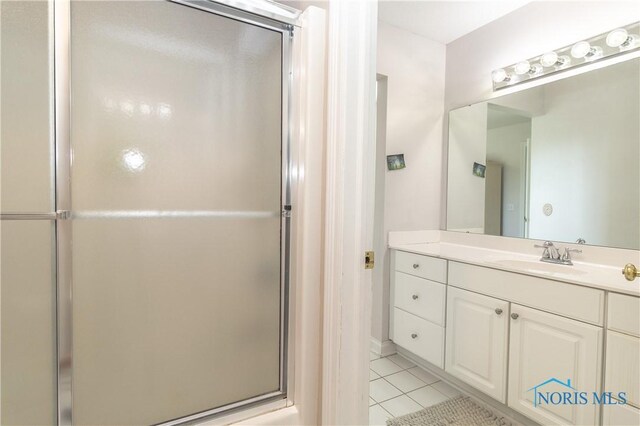 bathroom featuring a shower with shower door, vanity, and tile patterned flooring