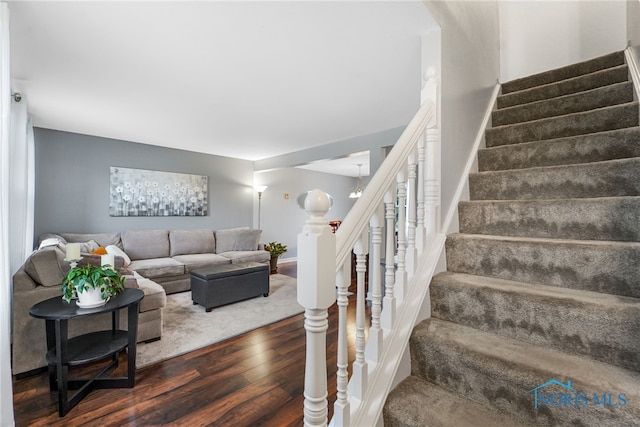 stairs with wood-type flooring and an inviting chandelier