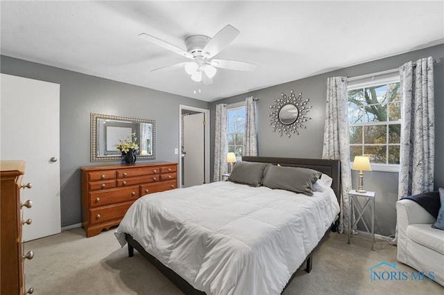 carpeted bedroom featuring multiple windows and ceiling fan