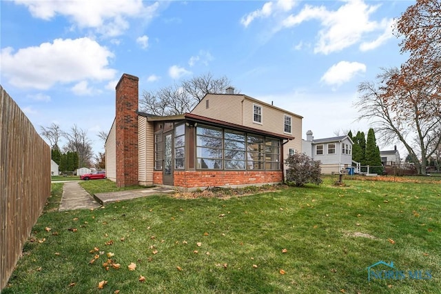 back of property featuring a yard and a sunroom