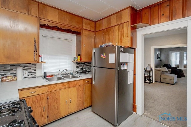 kitchen featuring decorative backsplash, sink, light hardwood / wood-style floors, and stainless steel refrigerator