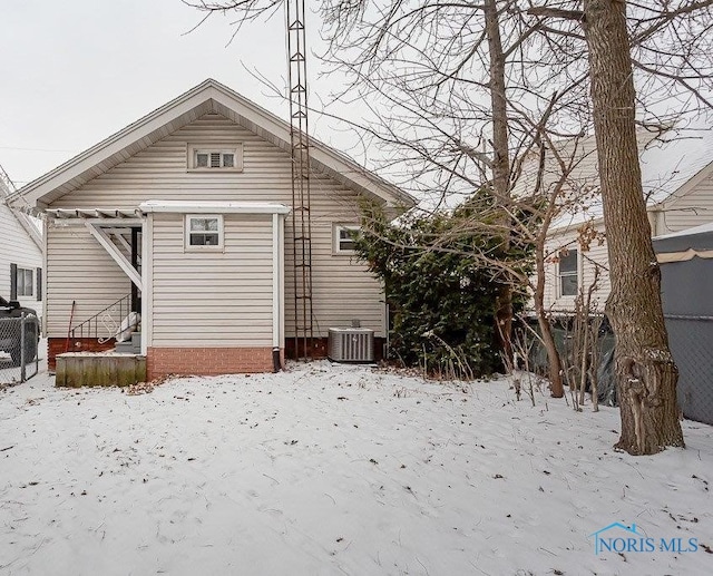 snow covered back of property featuring central air condition unit