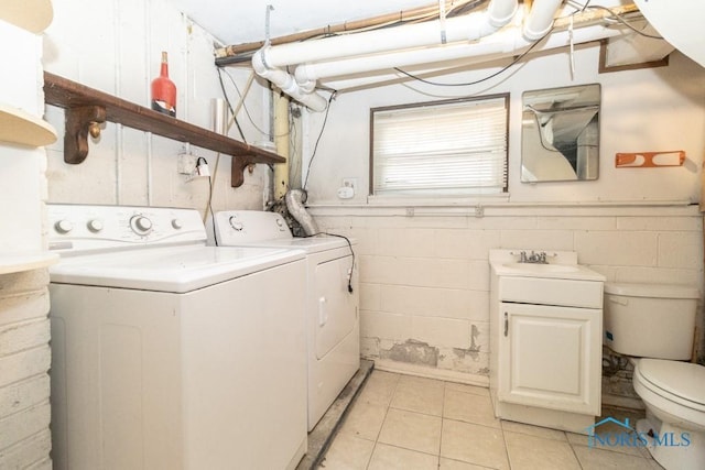 clothes washing area featuring light tile patterned floors, sink, and separate washer and dryer