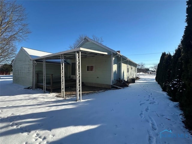 view of snowy exterior featuring a carport