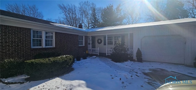 snow covered property entrance with a garage