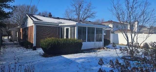 snow covered property featuring a sunroom