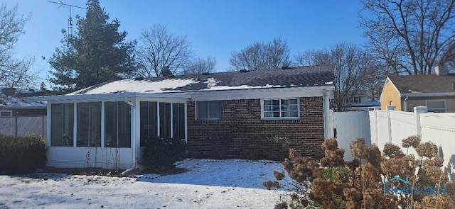 snow covered property with a sunroom