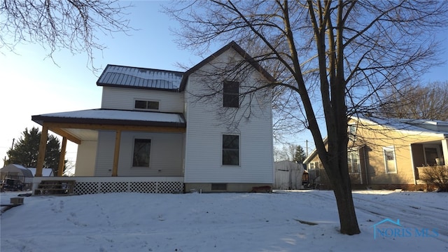 snow covered house featuring a porch