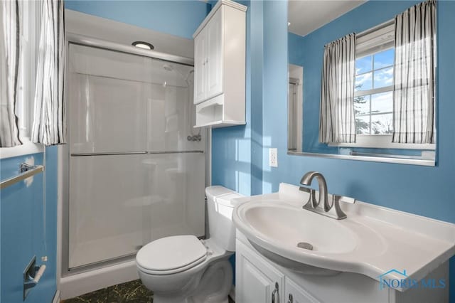 bathroom featuring vanity, toilet, and a shower with shower door