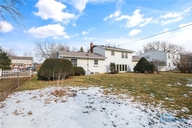 snow covered back of property featuring a lawn