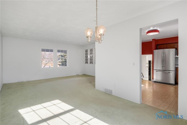 unfurnished dining area featuring an inviting chandelier and light carpet