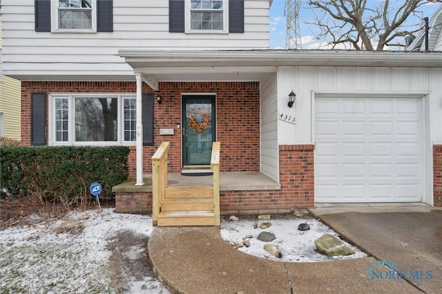 snow covered property entrance featuring a garage