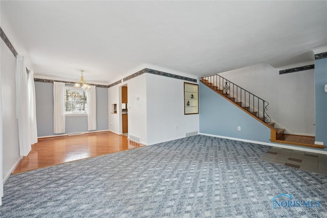 unfurnished living room featuring an inviting chandelier and carpet floors