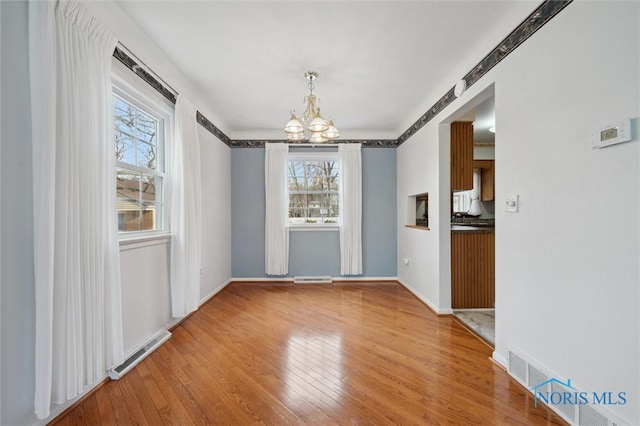 unfurnished dining area featuring a notable chandelier and light hardwood / wood-style floors