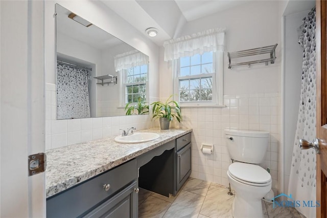 bathroom with vanity, toilet, and tile walls