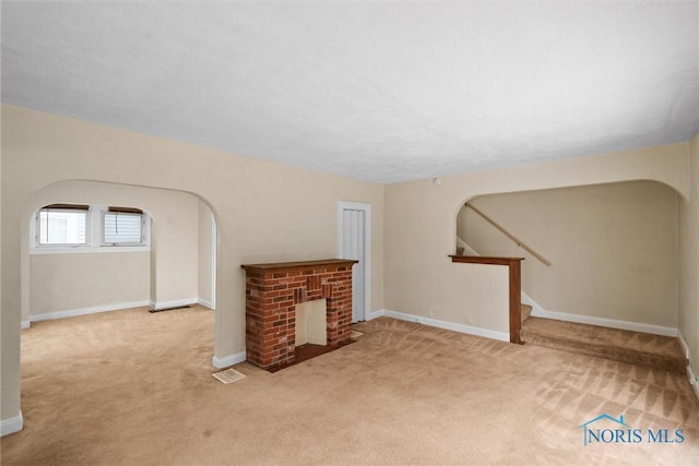 unfurnished living room featuring light carpet and a fireplace