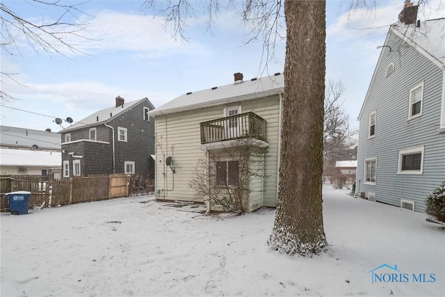 snow covered house featuring a balcony