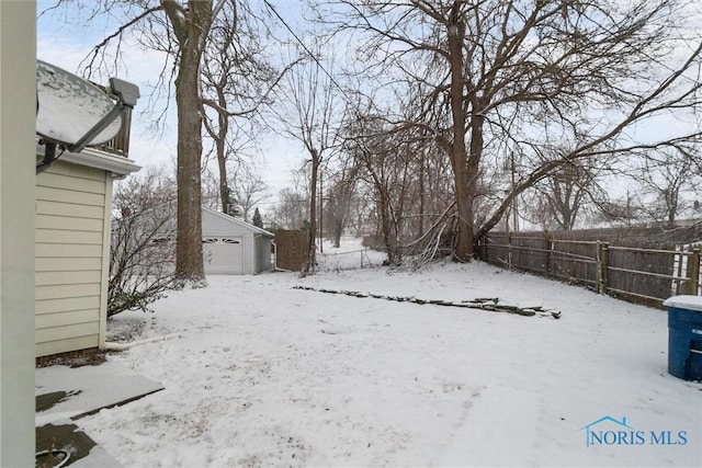 yard covered in snow featuring an outdoor structure and a garage