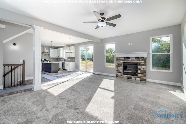 living room featuring ceiling fan with notable chandelier, a fireplace, light colored carpet, and a healthy amount of sunlight