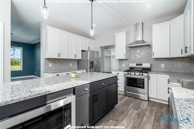 kitchen with hanging light fixtures, white cabinets, wall chimney exhaust hood, and stainless steel appliances