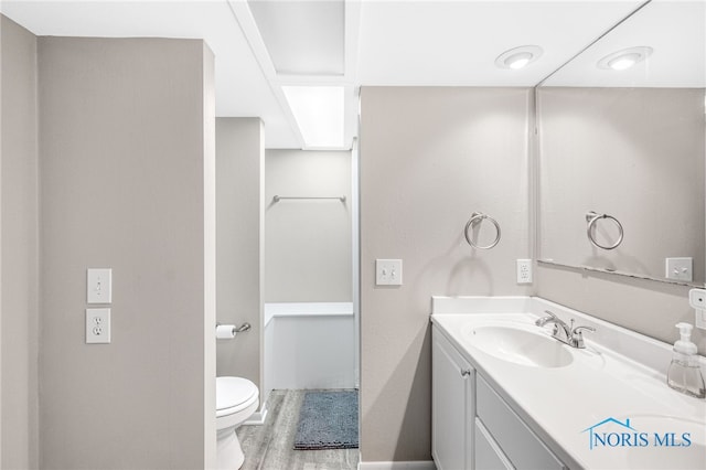 bathroom with toilet, hardwood / wood-style flooring, and vanity