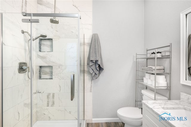 bathroom with toilet, vanity, wood-type flooring, and a shower with shower door