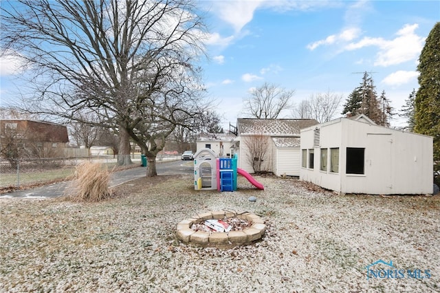 view of yard featuring a playground, an outdoor fire pit, and an outdoor structure