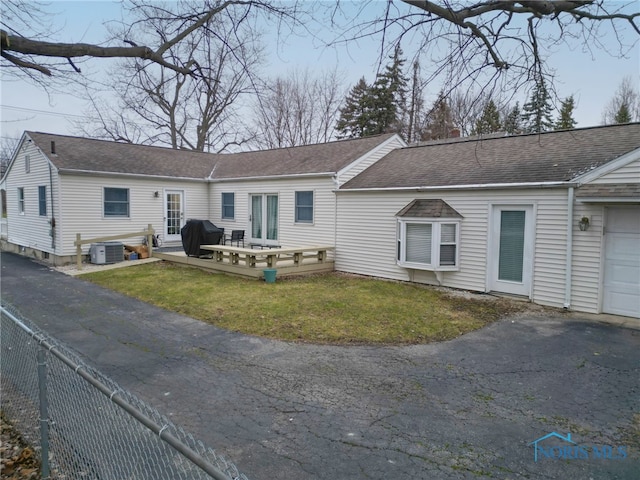 single story home featuring a front yard, a wooden deck, central AC, and a garage