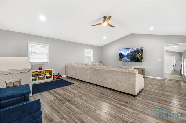 living room with ceiling fan, plenty of natural light, hardwood / wood-style floors, and vaulted ceiling