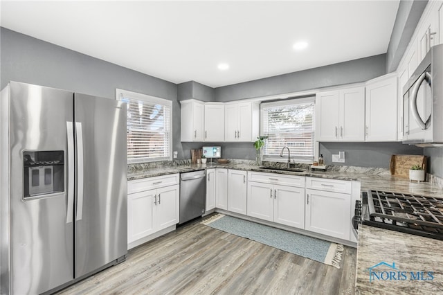 kitchen featuring stone counters, stainless steel appliances, white cabinetry, and sink