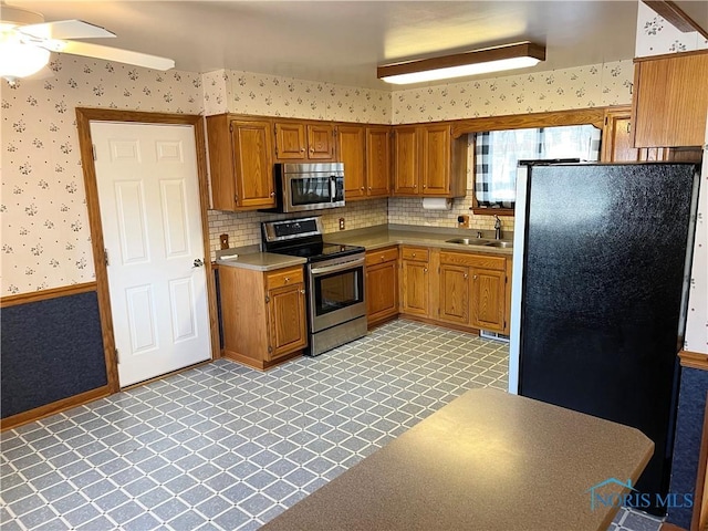 kitchen featuring ceiling fan, decorative backsplash, sink, and stainless steel appliances