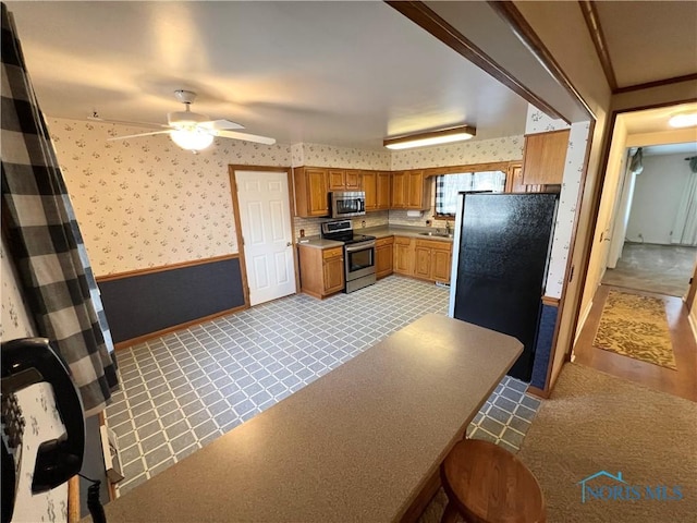 kitchen with ceiling fan, sink, appliances with stainless steel finishes, and light carpet