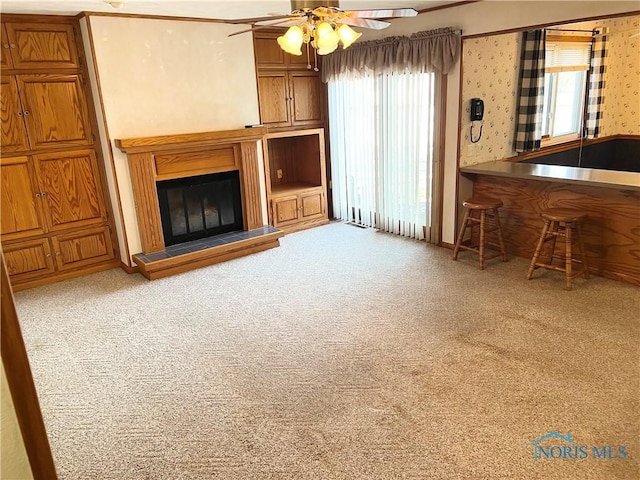 unfurnished living room featuring light carpet and ceiling fan