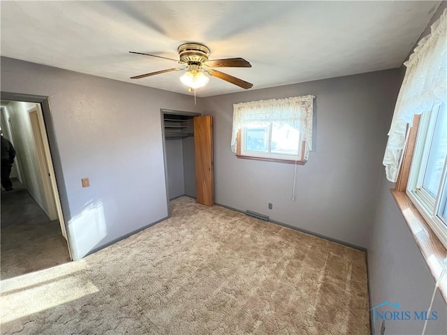 unfurnished bedroom featuring ceiling fan, a closet, and light carpet