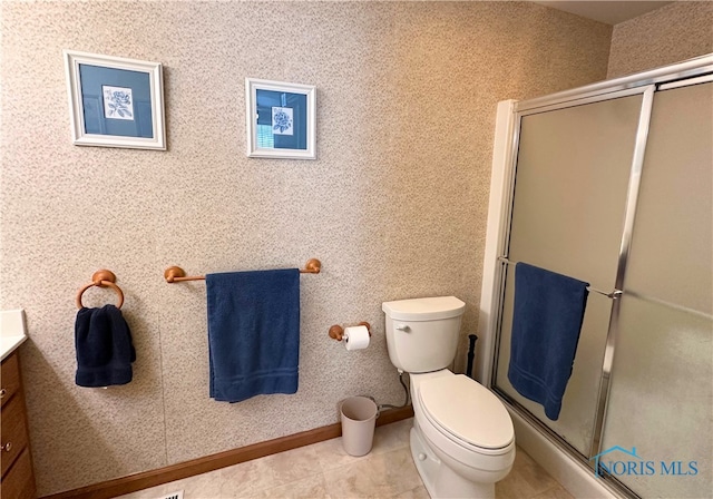 bathroom featuring vanity, toilet, a shower with door, and tile patterned flooring