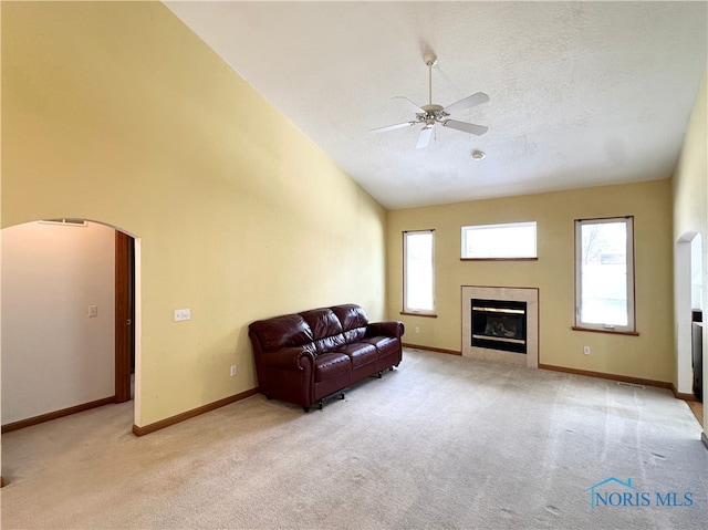 living room with light carpet, ceiling fan, high vaulted ceiling, and a textured ceiling