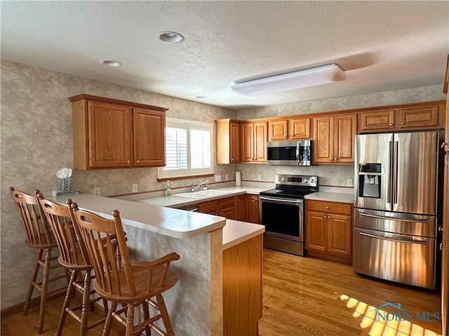 kitchen featuring stainless steel appliances, a breakfast bar, sink, and kitchen peninsula