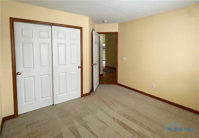 unfurnished bedroom featuring light colored carpet and a closet