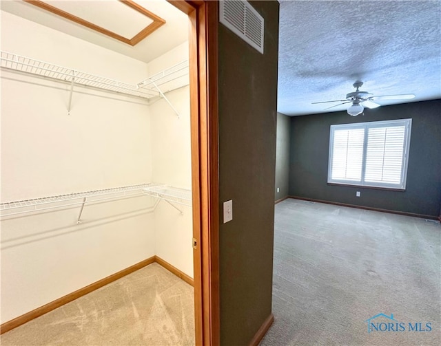 walk in closet with carpet and ceiling fan