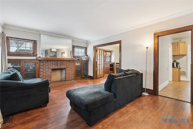 living room featuring wood-type flooring, a fireplace, french doors, and crown molding