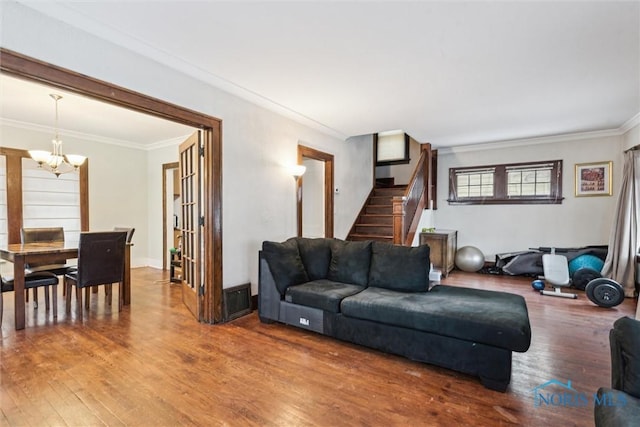 living room featuring hardwood / wood-style floors, ornamental molding, and an inviting chandelier