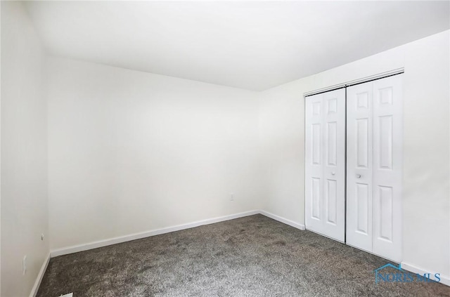 unfurnished bedroom featuring a closet and dark carpet