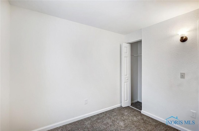 unfurnished bedroom featuring dark carpet and a closet