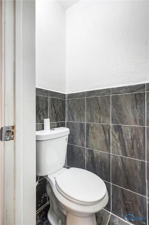 bathroom with tile walls and toilet