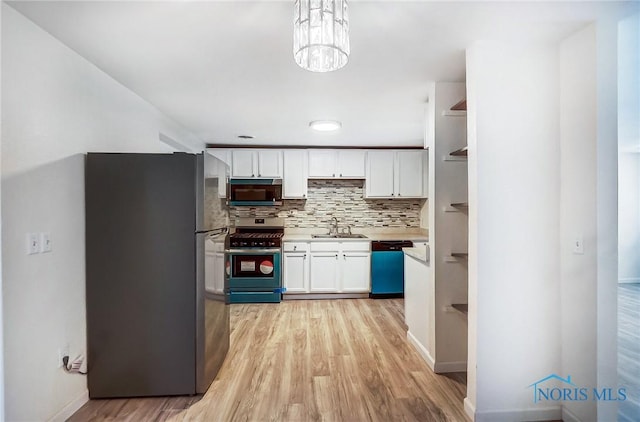 kitchen with decorative light fixtures, decorative backsplash, sink, white cabinetry, and stainless steel appliances