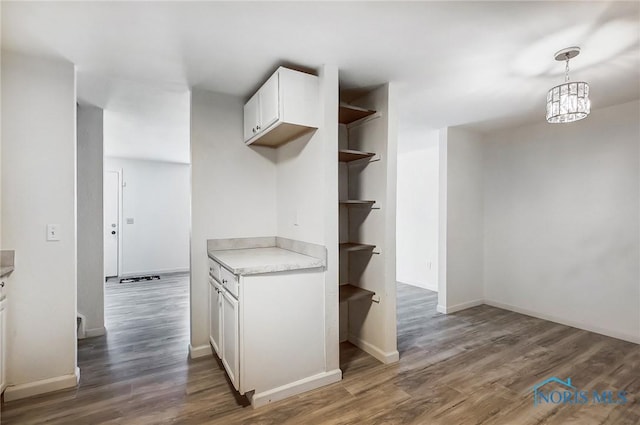 kitchen featuring white cabinetry, dark hardwood / wood-style flooring, an inviting chandelier, and hanging light fixtures